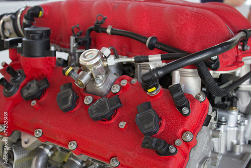 Detailed perspective of a car engine's red fuel rail and black injectors, components crucial for delivering fuel to the engine efficiently