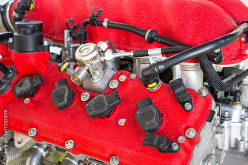 The robust red valve cover of a high-performance engine, with black fuel injectors and detailed linkages, showcases advanced automotive technology