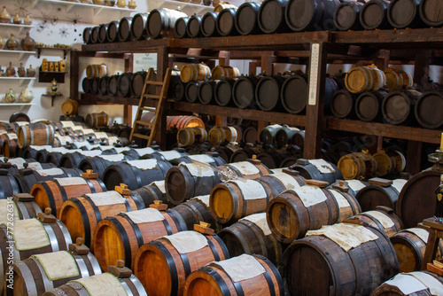 Rows of oak barrels dedicated to the aging of olive oil, arrayed in a well-maintained storage room, highlighting the art of olive oil refinement