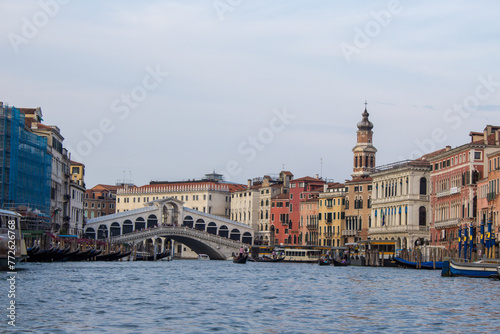 The Rialto Bridge stands proudly over the Grand Canal in Venice, framed by historic facades, under the watchful eye of a campanile in the distance. photo