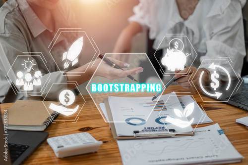 ฺBootstrapping concept, Business team analyzing income charts and graphs on office desk with bootstrapping icon on virtual screen.