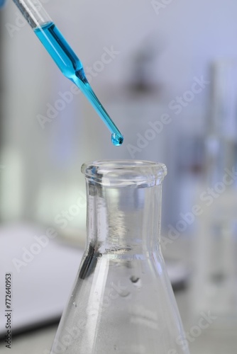 Laboratory analysis. Dripping liquid into flask on table, closeup