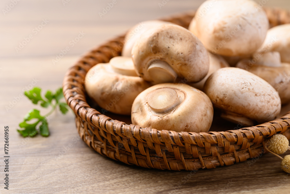 Fresh Champignon mushroom or button mushroom in natural basket on wooden background Fresh Champignon mushroom or button mushroom in natural basket on wooden background