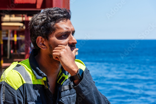 Lonely seafarer on board of the cargo ship, he is looking into the open sea thinking about his home and family. photo