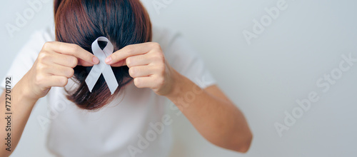 Woman having Headache with grey ribbon. Brain Cancer Awareness May month, World Brain Tumor day, Brain Stroke, Dementia, alzheimer, parkinson and world mental health concept