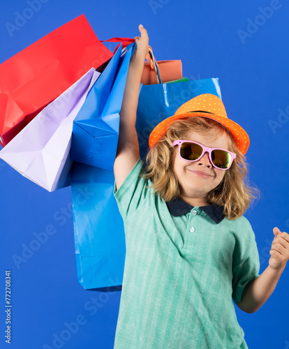 Little kid shopper. Child in fashion clothes on shopping. Kid with shopping packages. Shopper child with shopping bag posing shopping bags on studio background.