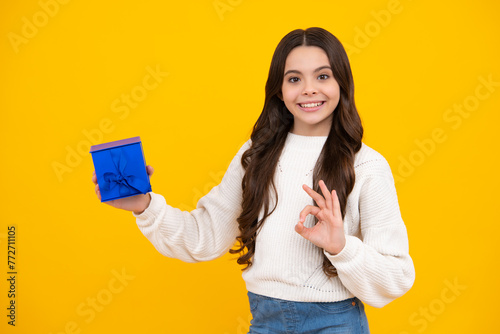 Teenager kid with present box. Teen girl giving birthday gift. Present, greeting and gifting concept. Happy face, positive and smiling emotions of teenager child.