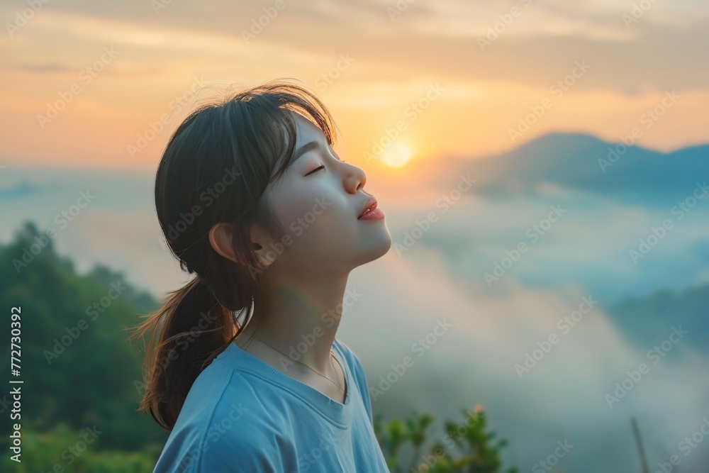 Asian woman enjoying the fresh morning air on the mountain, calming refreshing