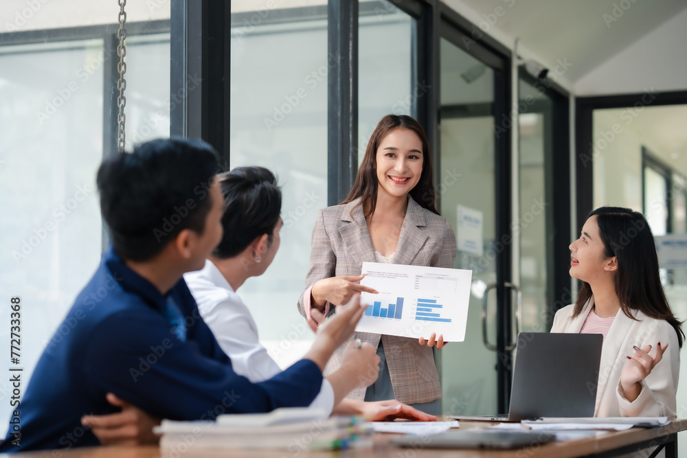 Businesswoman presenting graph chart to colleagues in a meeting. Professional corporate team discussion in modern office. Corporate business and teamwork concept.