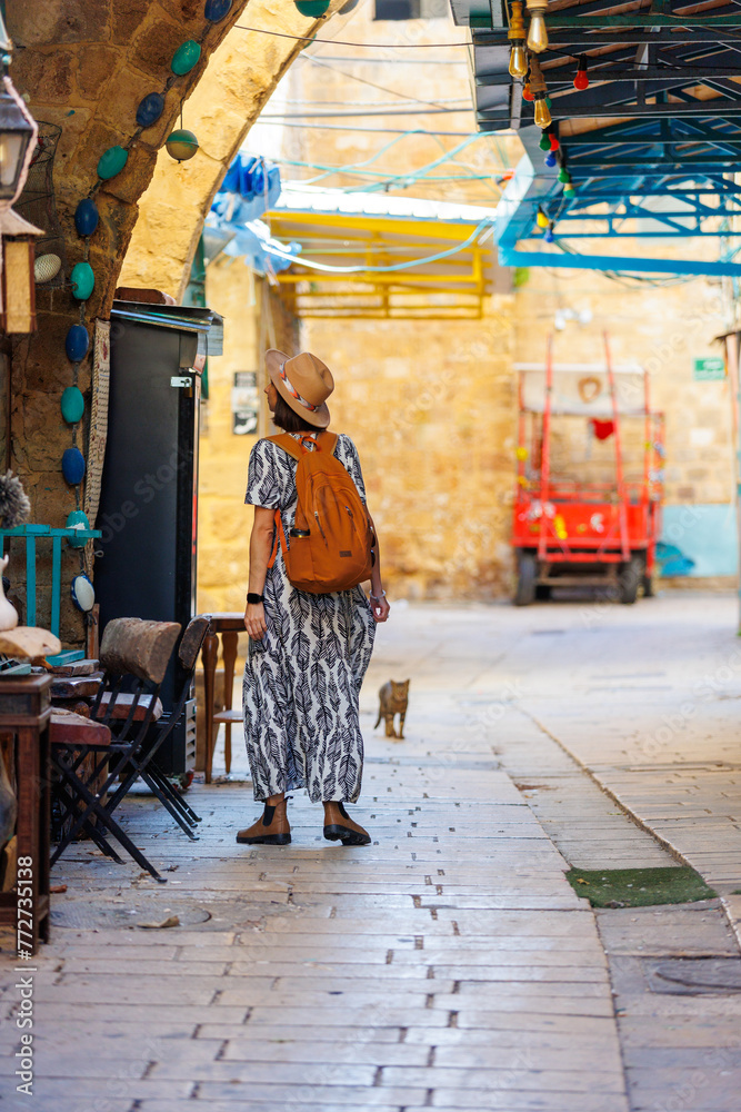 Beautiful girl traveler in a hat and with a backpack exploring the historical city.