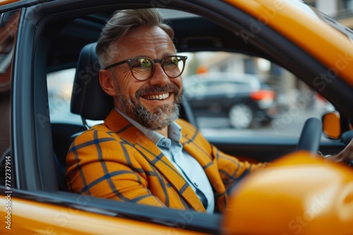 Stylish mature man in a trendy yellow jacket enjoying a ride in a modern car. Portrait of a cheerful, fashionable older man with a beard  © Fat Bee