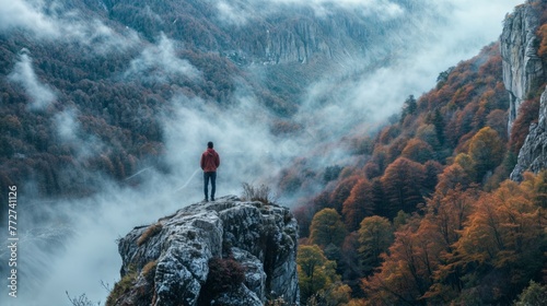 Man standing on the edge of a cliff in the autumn forest. photo