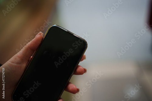 A smartphone with a blank black screen in his hand. A place for an inscription or image. modern means of communication.