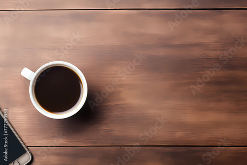 A cup of coffee and mobile phone on the table, top view, brown wooden background