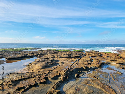 Low tide and the rock platform near Newcastle Ocean Baths, New South Wales, Australia. Green algae on the rocks, with surf crashing over the rocks.