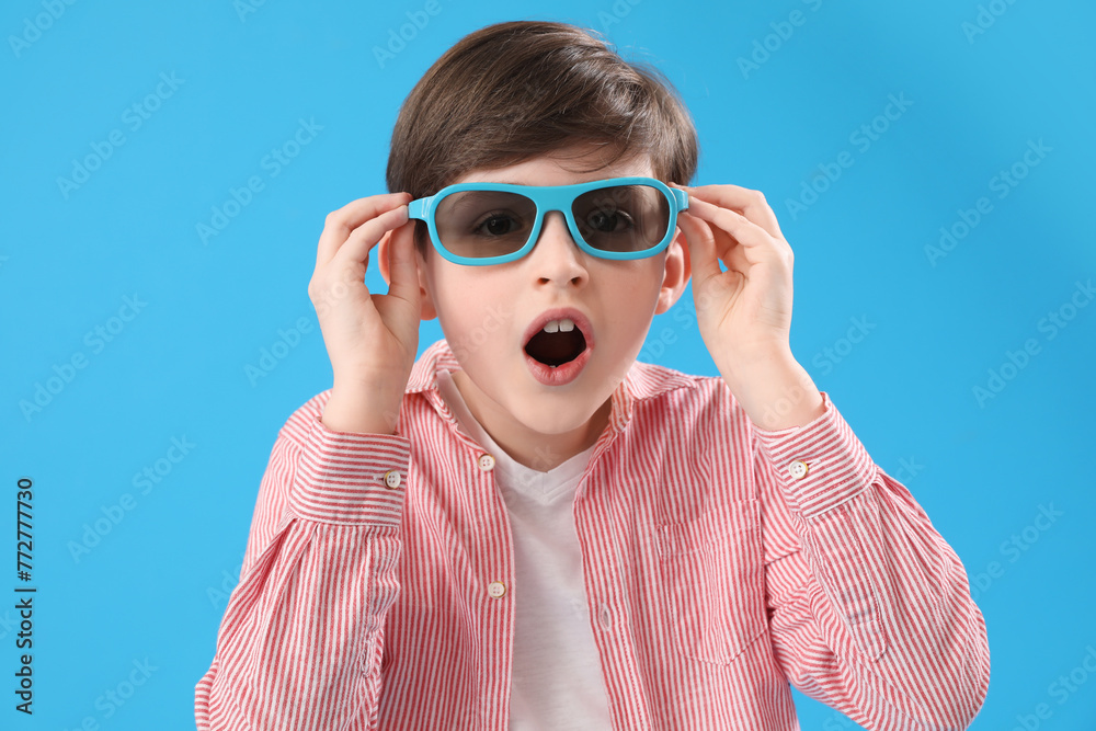 Shocked little boy in 3D glasses on blue background, closeup. Children's Day celebration Shocked little boy in 3D glasses on blue background, closeup. Children's Day celebration