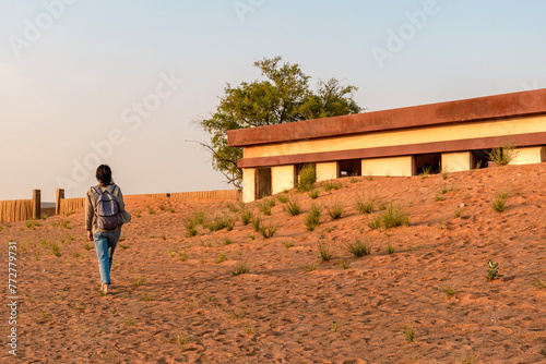 a tourist with a backpack walks through the ghost town of Al Madam, buried in sand dunes in the desert, Sharjah, United Arab Emirates