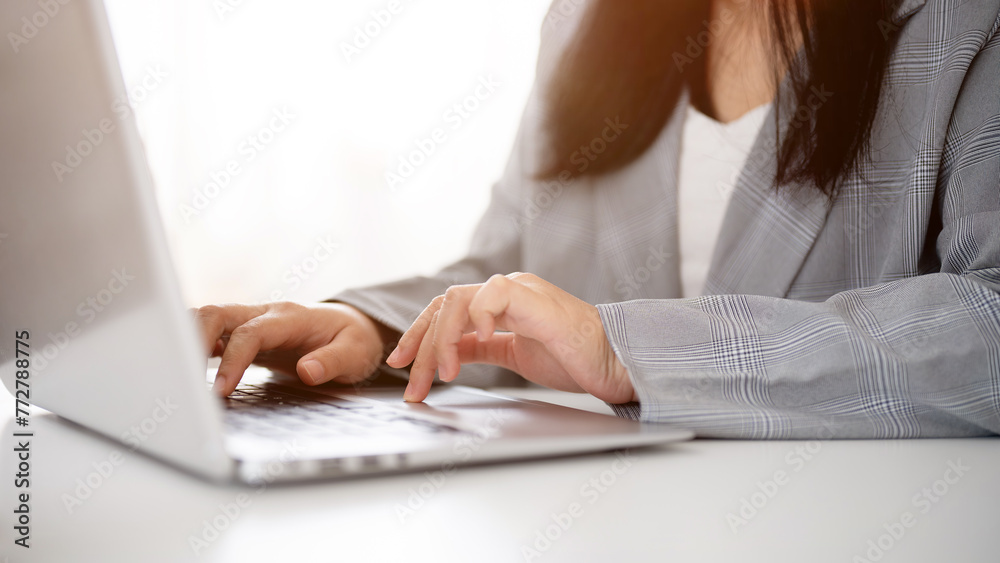 A cropped image of a businesswoman working or browsing on the laptop, working in a modern office. A cropped image of a businesswoman working or browsing on the laptop, working in a modern office.