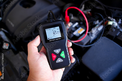 Battery tester in a auto mechanic hand for battery voltage or battery health analysis , Car maintenance concept photo