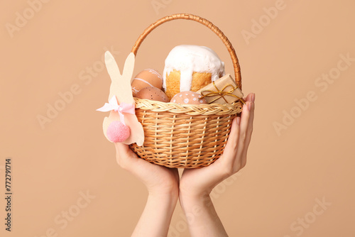 Female hands holding basket for Easter on beige background