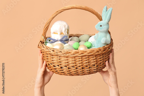 Female hands holding basket for Easter on beige background