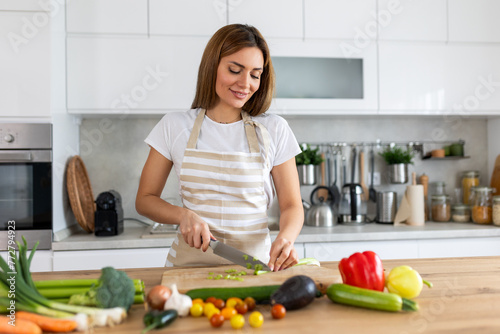 Beautiful young woman stand at modern kitchen chop vegetables prepare fresh vegetable salad for dinner or lunch  young woman cooking at home make breakfast follow healthy diet  vegetarian concept