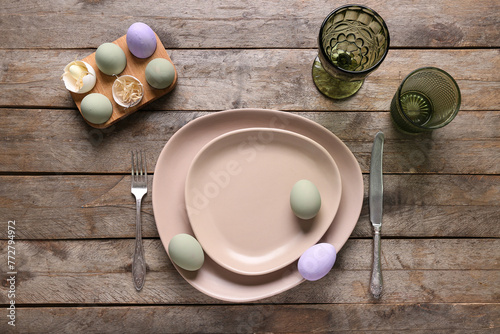 Table setting for Easter celebration with painted eggs on wooden background. Top view
