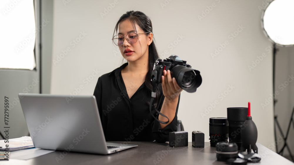 A professional Asian female photographer is focusing on checking images on her laptop. A professional Asian female photographer is focusing on checking images on her laptop.