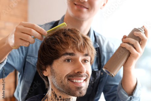 Male hairdresser spraying client's hair in barbershop, closeup