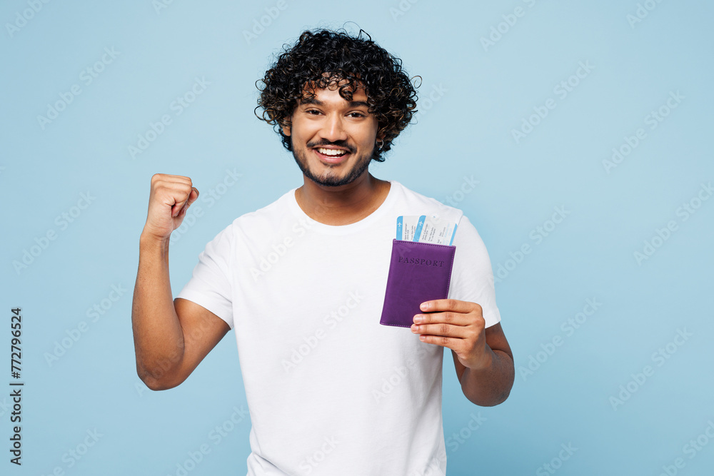 Traveler Indian man wear casual clothes hold passport ticket do winner gesture isolated on plain blue background. Tourist travel abroad in free spare time rest getaway Air flight trip journey concept Traveler Indian man wear casual clothes hold passport ticket do winner gesture isolated on plain blue background. Tourist travel abroad in free spare time rest getaway Air flight trip journey concept