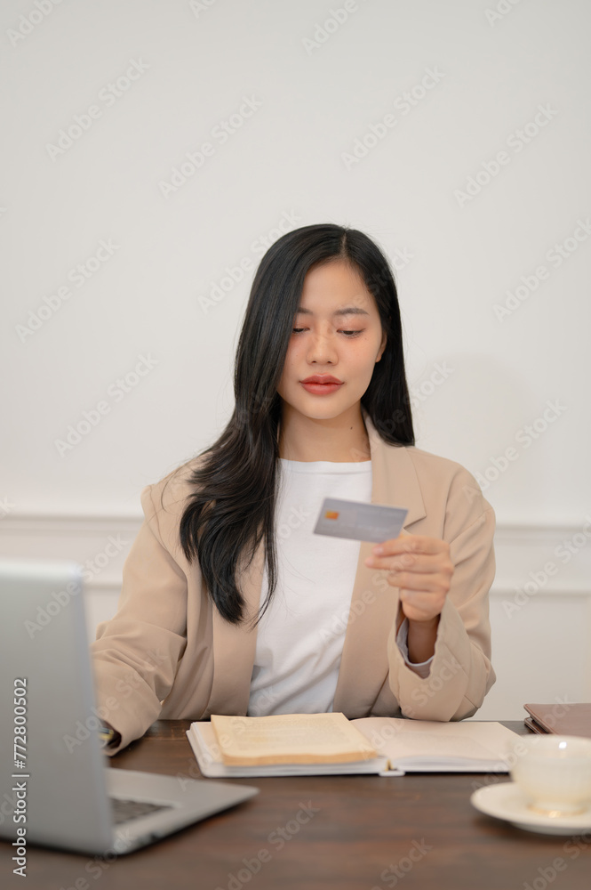 An attractive Asian businesswoman is registering her credit card on the website An attractive Asian businesswoman is registering her credit card on the website