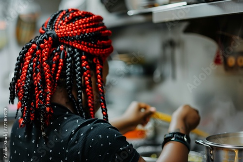 person with red and black braided hair cooking in kitchen