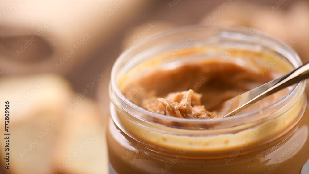 Peanut butter in a glass jar. Creamy smooth peanut butter. Mixing with a knife, making sandwich, organic food. American cuisine. Slow motion Peanut butter in a glass jar. Creamy smooth peanut butter. Mixing with a knife, making sandwich, organic food. American cuisine. Slow motion