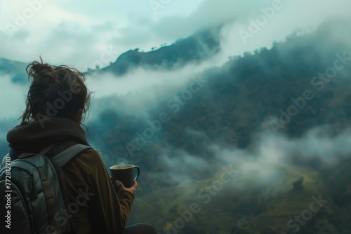 traveler with a coffee mug watching the fog roll over a mountain range