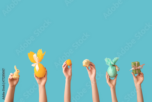 Female hands with gift eggs, chick, bunny and Easter egg on blue background