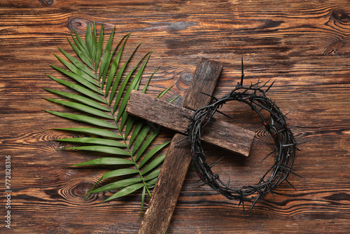 Crown of thorns with cross and palm leaf on wooden background. Good Friday concept