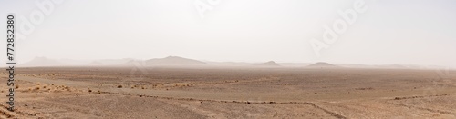 panorama desert landscape with arid hlls in the distance under a hazy sandstorm sky in southern Morocco © makasana photo
