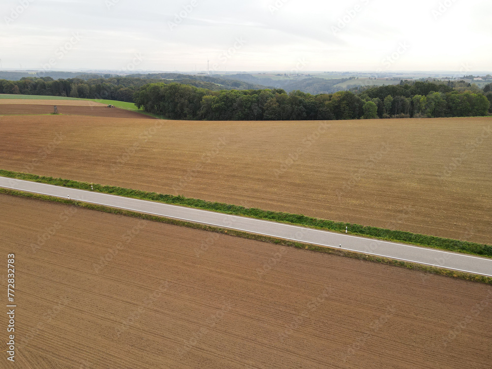 Aerial view of a asphalt road between farm fields with soil in the countryside Aerial view of a asphalt road between farm fields with soil in the countryside