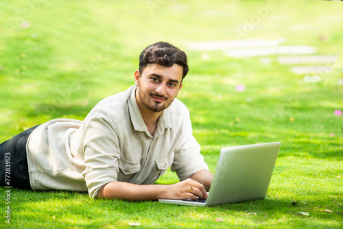 Indian man sitting on glass and using computer