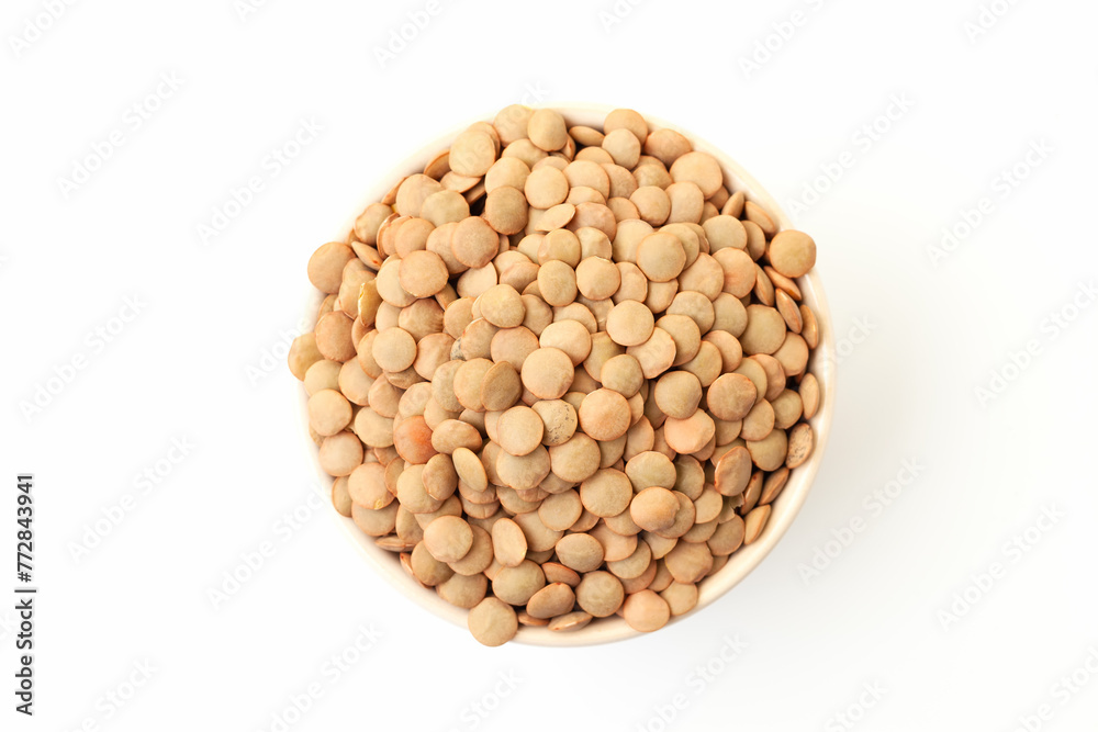 Uncooked brown lentils in bowl on white background. Dry brown lentil grains. Top view Uncooked brown lentils in bowl on white background. Dry brown lentil grains. Top view