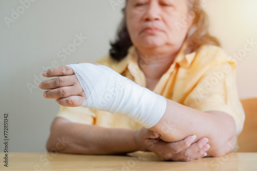 Asian old woman arm with gauze bandage on it. Sprain, stress fracture or repetitive strain injury in hand. photo
