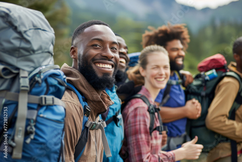 Group of happy friends with backpacks smiling at camera while hiking in mountains 