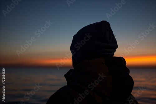 overtheshoulder shot of a fisherman gazing at the horizon as dawn breaks