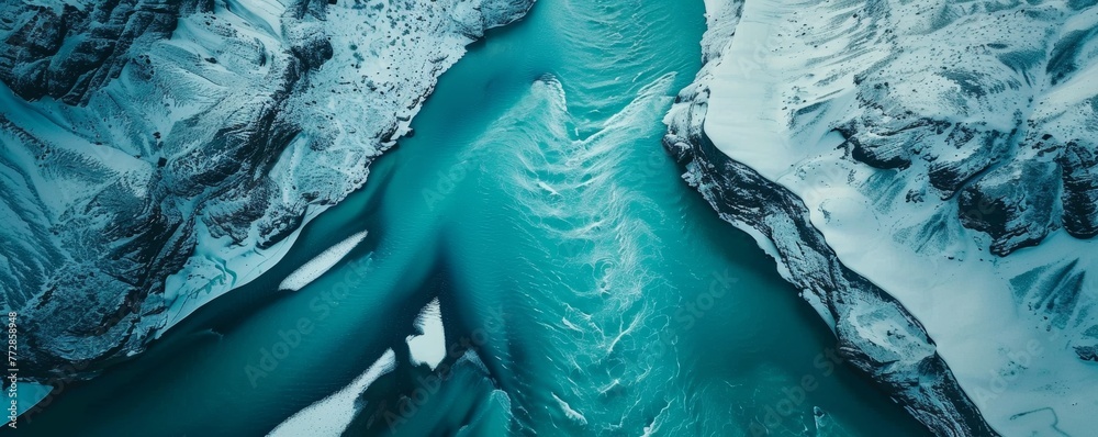 Aerial view of a glacial river between snow-capped mountains