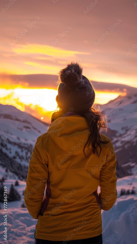 Woman watching sunset over snowy mountains