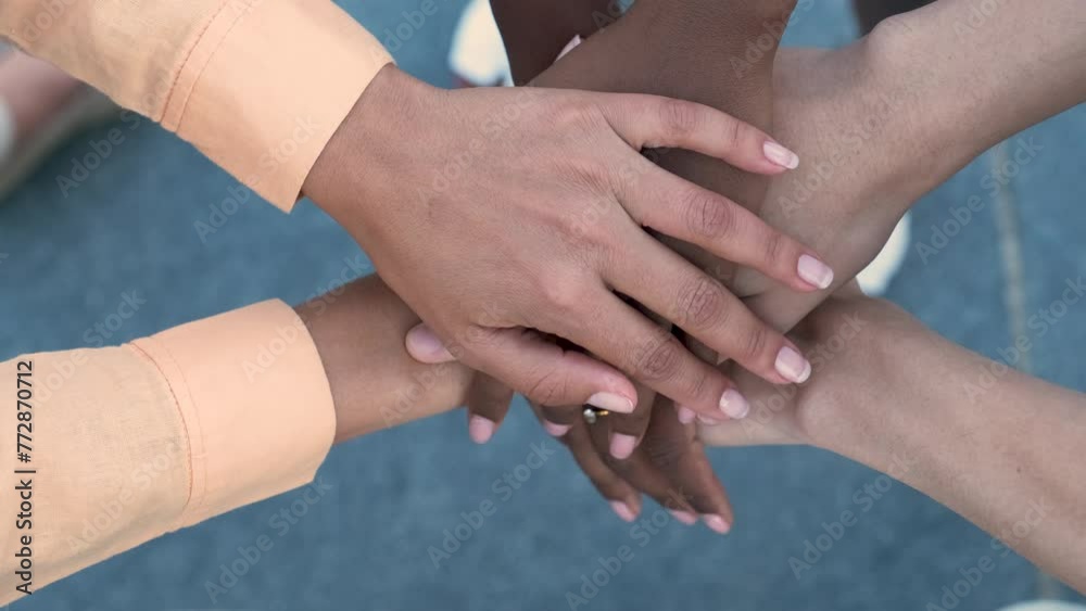 Close up top view of three young multiracial people putting their hands together showing unity and teamwork.