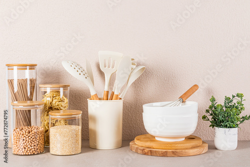 Beautiful kitchen background with bulk food storage area, spoons and cooking tools and green plant in a pot. Front view.