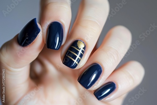 fingers with glossy navy polish and a single goldstriped accent photo