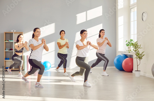 Group of fit and active female group doing sport exercises in gym. Happy smiling women in sportswear having workout indoors together. Sport training, exercising and fitness concept.