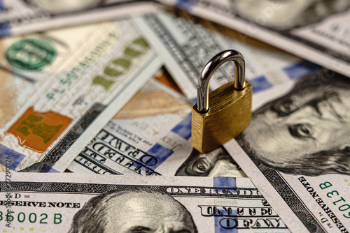 Padlock on hundred dollar bills. Financial security or lock concept. © Eugene_Photo